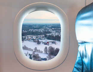 Fototapeta na wymiar Aerial view of snow covered Norwegian villagesas seen through window of an commerical passenger airplane - Oslo, Norway 