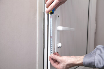 Caucasian man measuring door in room.