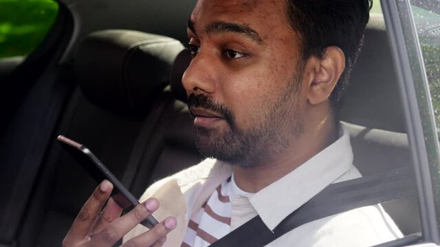 transport, business and technology concept - happy smiling indian male passenger or businessman using voice command recorder on smartphone on back seat of taxi car