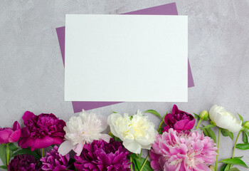 A clean sheet of paper with peony flowers on a concrete background. Blank for a greeting card or invitation, mock-up