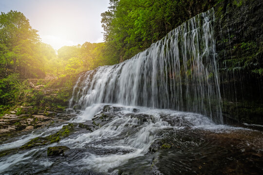 Waterfall surrounded by moss, trees, and stones in Ystradfellte Neath UK