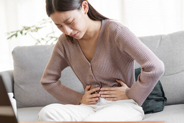 Obraz premium Flatulence asian young woman, girl hand in stomach ache, suffer from food poisoning, abdominal pain and colon problem, gastritis or diarrhoea. Patient belly, abdomen or inflammation, concept.