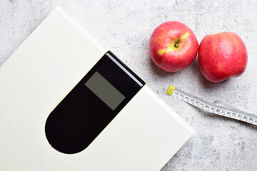 Concept of health, maintaining proper weight and good nutrition. Digital scale and two apples, along with a tape measure. Copy space.