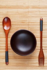 Natural wood plate, spoon and fork on a bamboo backing.