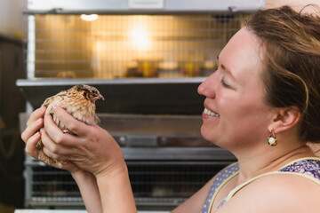 woman farmer holding domestic quail indoors