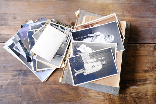 stack of vintage photos, retro photography of 1940-1950 on wooden table, old books, concept of genealogy, memory of ancestors, family tree, genealogy, childhood memories, family archive