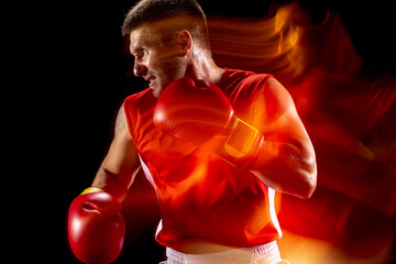 Cropped portrait of professional male boxer training on black studio background in mixed lights....