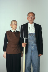 Elderly man and woman in art performance, replica of painting american gothic. Retro style,...