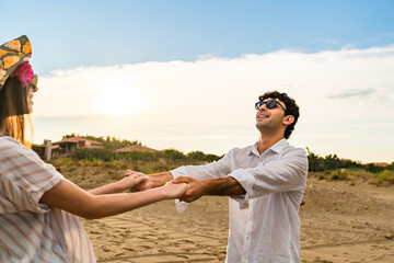Couple spinning together holding hands in the beach. Romance and vacation concept.