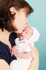 Loving mother holds infant baby.A woman plays with her daughter isolated on blue background. The concept of happy motherhood.