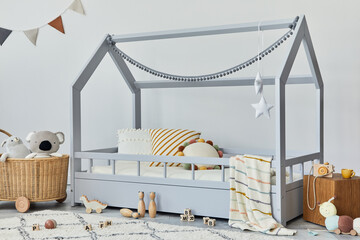 Stylish scandinavian child's room with creative wooden bed, rattan basket, wooden shelf, plush and...