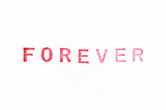 Red color rubber stamp in word forever on white paper background