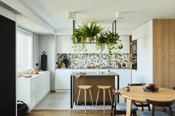 Stylish kitchen interior design with dining space. Workspace with kitchen accessories on the back ground. Creative walls with woode pannels. Minimalistic style an plant love concept.