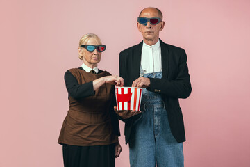 Serious elderly man and woman in retro vintage farmer outfits isolated on pink studio background....