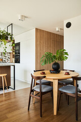 Stylish dining room interior design with dining table. Workspace with kitchen accessories on the background. Creative walls, white and wooden pannels. Minimalistic style an plant love concept.