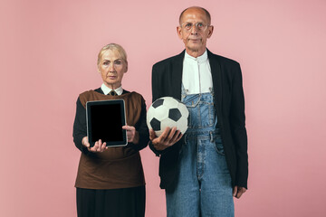 Serious elderly man and woman in retro vintage farmer outfits isolated on pink studio background....