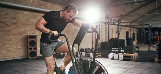 Muscular male working out on cycling machine