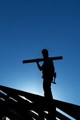 Worker on roof structure of building backlit by the setting sun