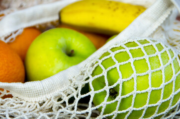 Eco bag with fruits (bananas, apples, oranges) close-up
