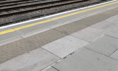 Train platform showing yellow safety line on paving and railway tracks