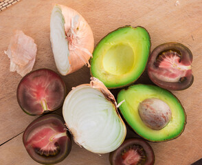 vegetables black tomatoes, avocado and onions on wooden board