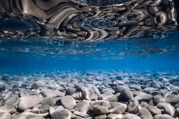 Obraz premium Underwater view with stones bottom, reflection in sea water. Ocean background
