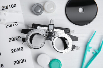 Different ophthalmologist tools on white wooden background, flat lay