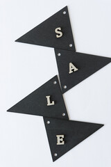 the word "sale" in silver glitter letters and retro black merchandise tags on a light background