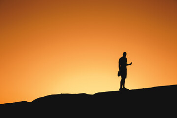 Silhouette of a man standing on a mountain at sunset