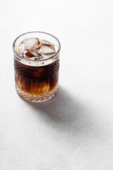 Cold drink with espresso and tonic in glass on white background with shadows, vertical