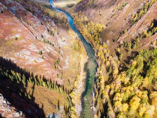In the gorge below there is a mountain river, Evening light of the sun, autumn grasses and...