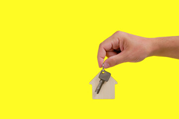 House keys with a keychain in hand on a yellow background.