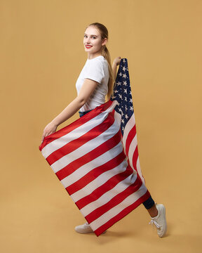 attractive blonde poses with an American flag. photo shoot in the studio on a yellow background