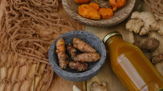 Bottle of Jamu drink- Indonesian herbal beverage with natural ingredients: turmeric, ginger, lime, palm sugar, lemongrass, tamarind on wooden table. Healthy lifestyle