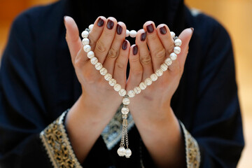 Close up of a Muslim woman's hands in abaya while holding rosary and praying, United Arab Emirates