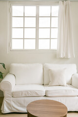 White sofa with window in a white room.