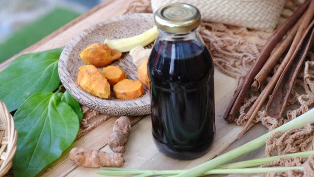 Many different Jamu drinks- Indonesian herbal beverage in glass bottles with natural ingredients: turmeric, ginger, lime, palm sugar, lemongrass, tamarind on wooden table. Healthy lifestyle