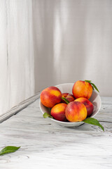Peaches in a plate on a wooden table, nectarine.Selective focus