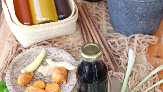 Many different Jamu drinks- Indonesian herbal beverage in glass bottles with natural ingredients: turmeric, ginger, lime, palm sugar, lemongrass, tamarind on wooden table. Healthy lifestyle