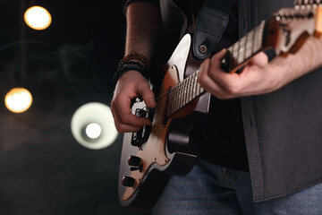 Man playing electric guitar on stage, closeup. Rock concert