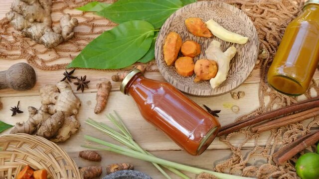 Many different Jamu drinks- Indonesian herbal beverage in glass bottles with natural ingredients: turmeric, ginger, lime, palm sugar, lemongrass, tamarind on wooden table. Healthy lifestyle.