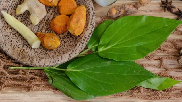Many different Jamu drinks- Indonesian herbal beverage in glass bottles with natural ingredients: turmeric, ginger, lime, palm sugar, lemongrass, tamarind on wooden table. Healthy lifestyle. Flat lay
