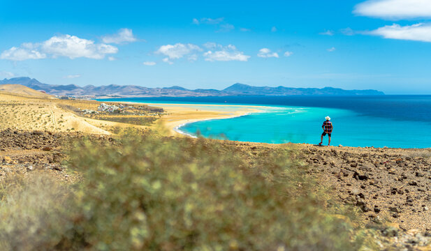 Tourist with straw hat looking at the ocean from Mirador Del Salmo viewpoint, Costa Calma, Fuerteventura, Canary Islands, Spain