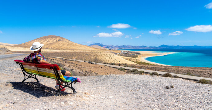 Tourist admiring the crystal ocean from a bench at Mirador Del Salmo viewpoint, Costa Calma, Fuerteventura, Canary Islands, Spain