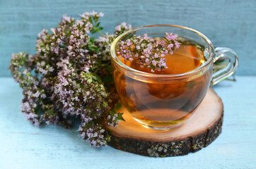 Oregano tea in a glass cup on a bue wooden background.Healthy drink,diet,alternative therapy or...