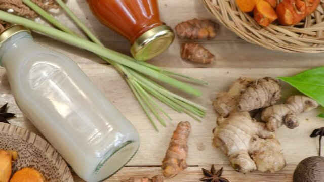 Many different Jamu drinks- Indonesian herbal beverage in glass bottles with natural ingredients: turmeric, ginger, lime, palm sugar, lemongrass, tamarind on wooden table. Healthy lifestyle. Flat lay
