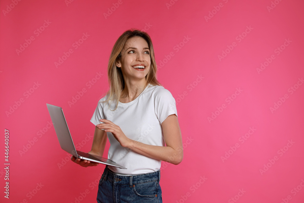 Wall mural young woman with modern laptop on pink background