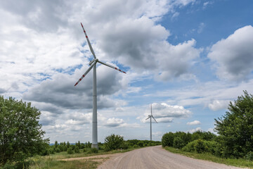 Fototapeta na wymiar rotating blades of a windmill propeller on blue sky background. Wind power generation. Pure green energy.