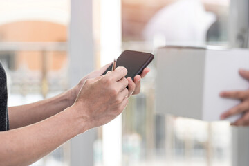 Women use electronic pen Sign and check list on smartphone after check pick up package from the post office transport,stay at home concept