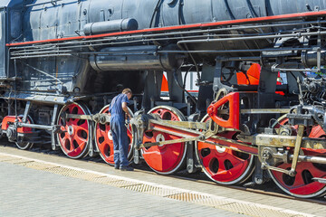 Worker inspects a black retro steam locomotive on the railway platform of the Rizhsky station. Moscow, Russia
